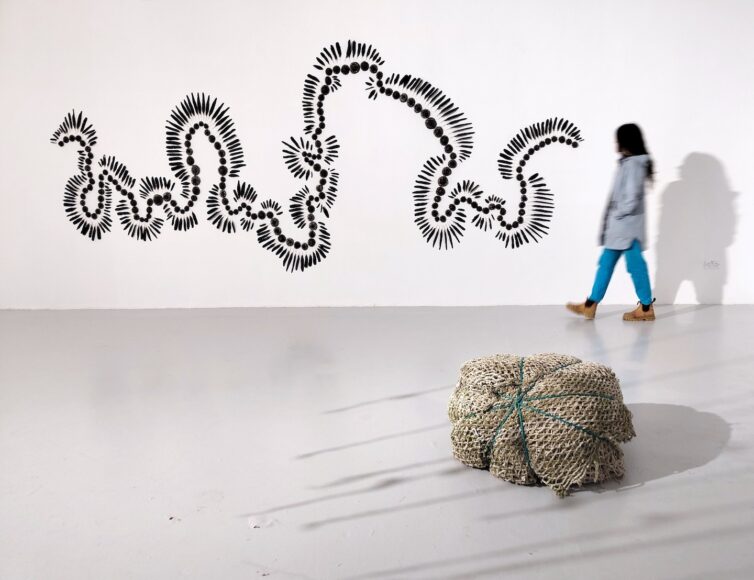 All Find Refuge from the Hammering Sea Sligo to Adrara, view 5, 2026, stoneware glaze ground foraged corvid feathers 216x 95x3 inches in installation.